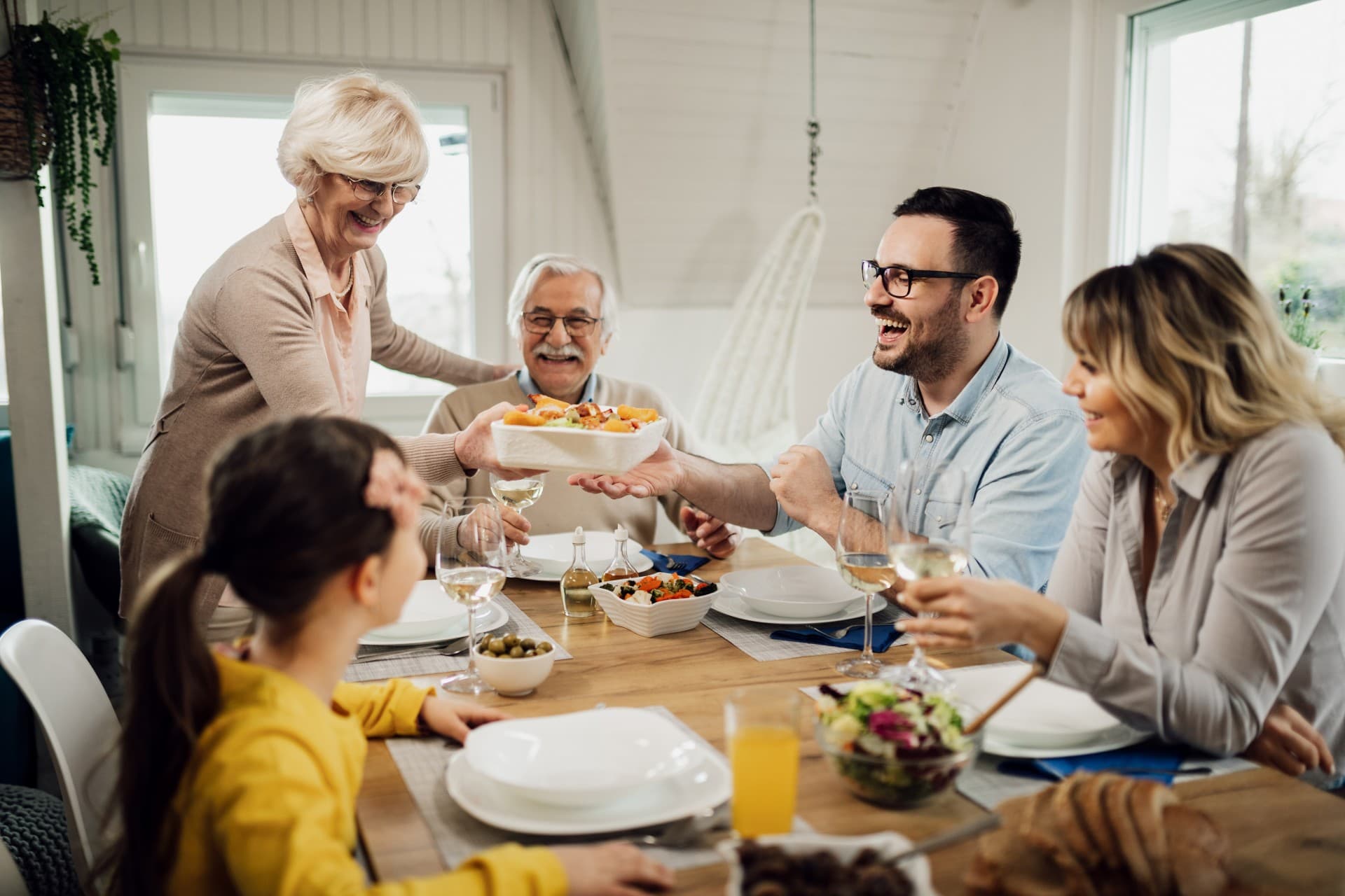 happy multigeneration family having lunch together home senior woman is bringing food table